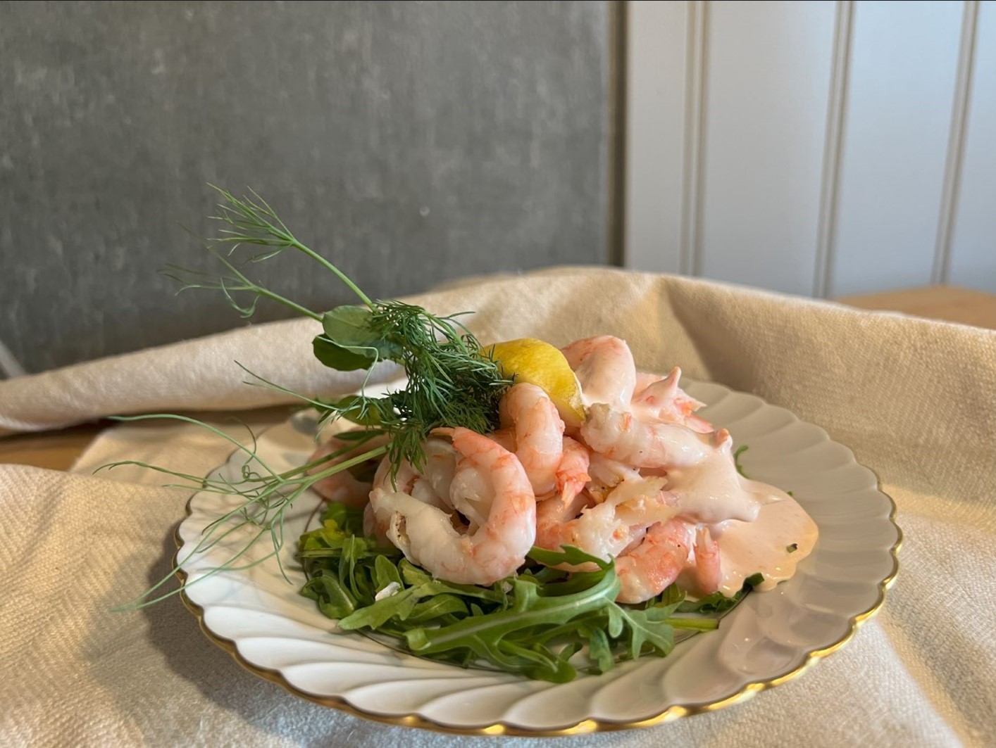 Reker dandert på en tallerken. Oppå en salat.